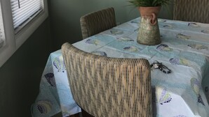 Un comedor con una mesa cubierta con un mantel estampado, rodeada de sillas. Hay una planta en maceta sobre la mesa, y un cuadro en la pared encima.