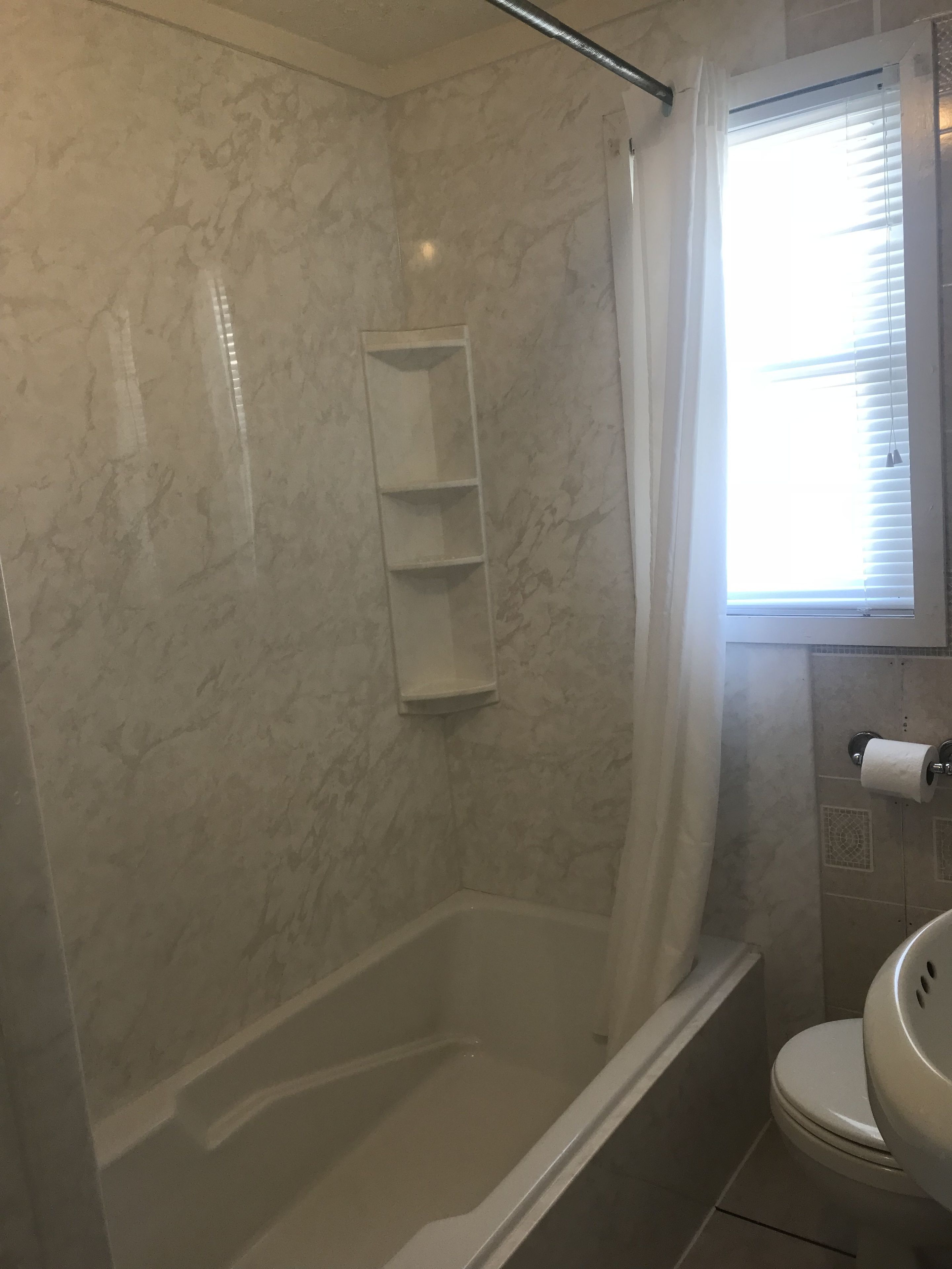 A bathroom with a shower, toilet, and marble walls.