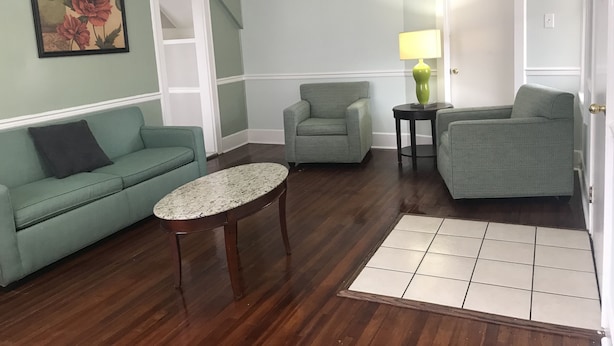 Una sala de estar con un sofá verde, un sillón a juego, una mesita redonda y una puerta.