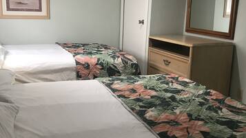 A bedroom with two single beds, a wooden dresser, a mirror, and a framed picture on the wall.