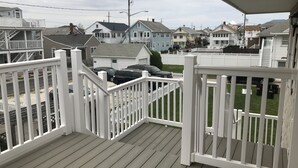 Una terraza de madera con barandillas blancas que da a una calle residencial.