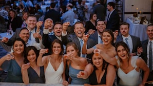 Un grupo de personas en un evento social en un amplio espacio interior con mesas y sillas dispuestas para comer o conversar.