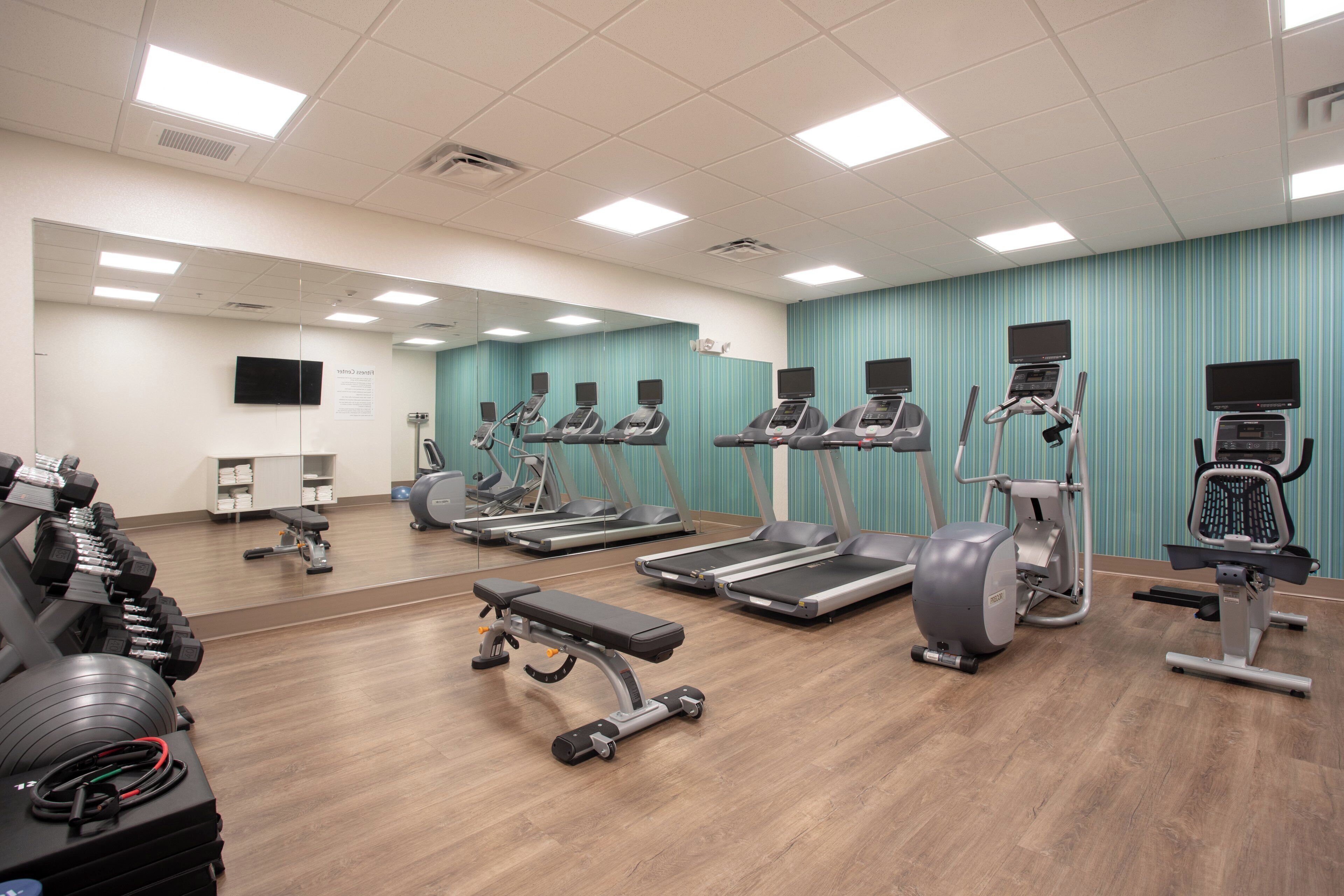 A gym with treadmills, elliptical machines, and free weights.
