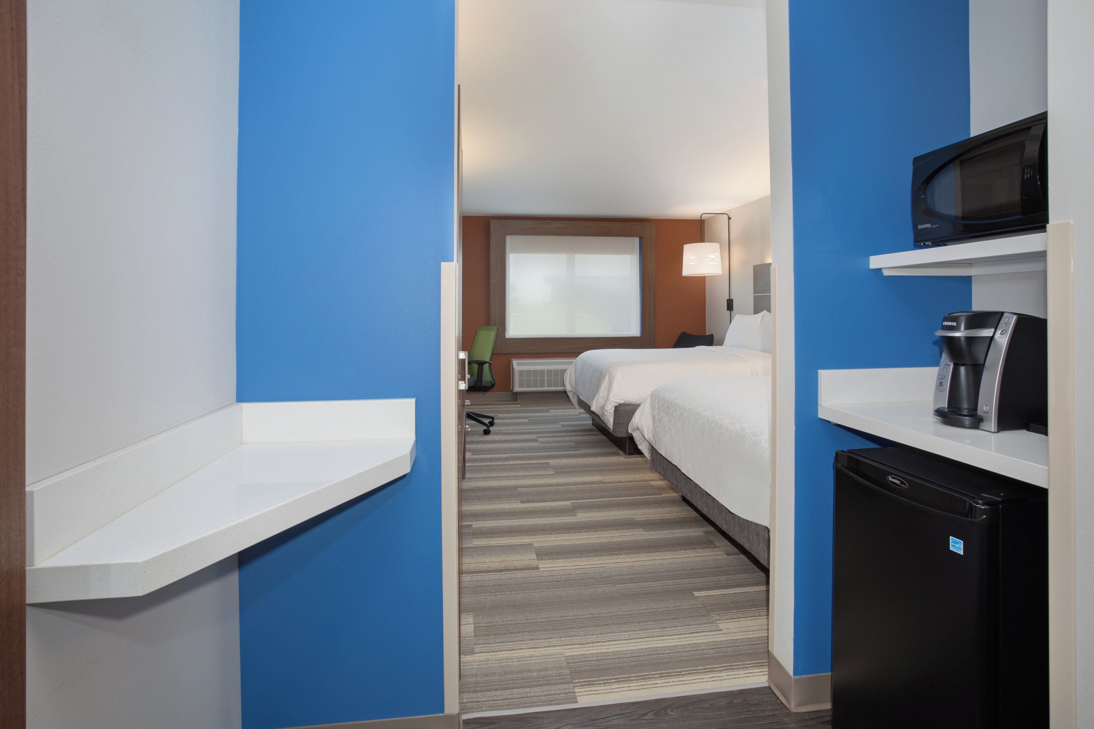 A hotel room with a bed, a microwave, a coffee maker, and a small refrigerator.