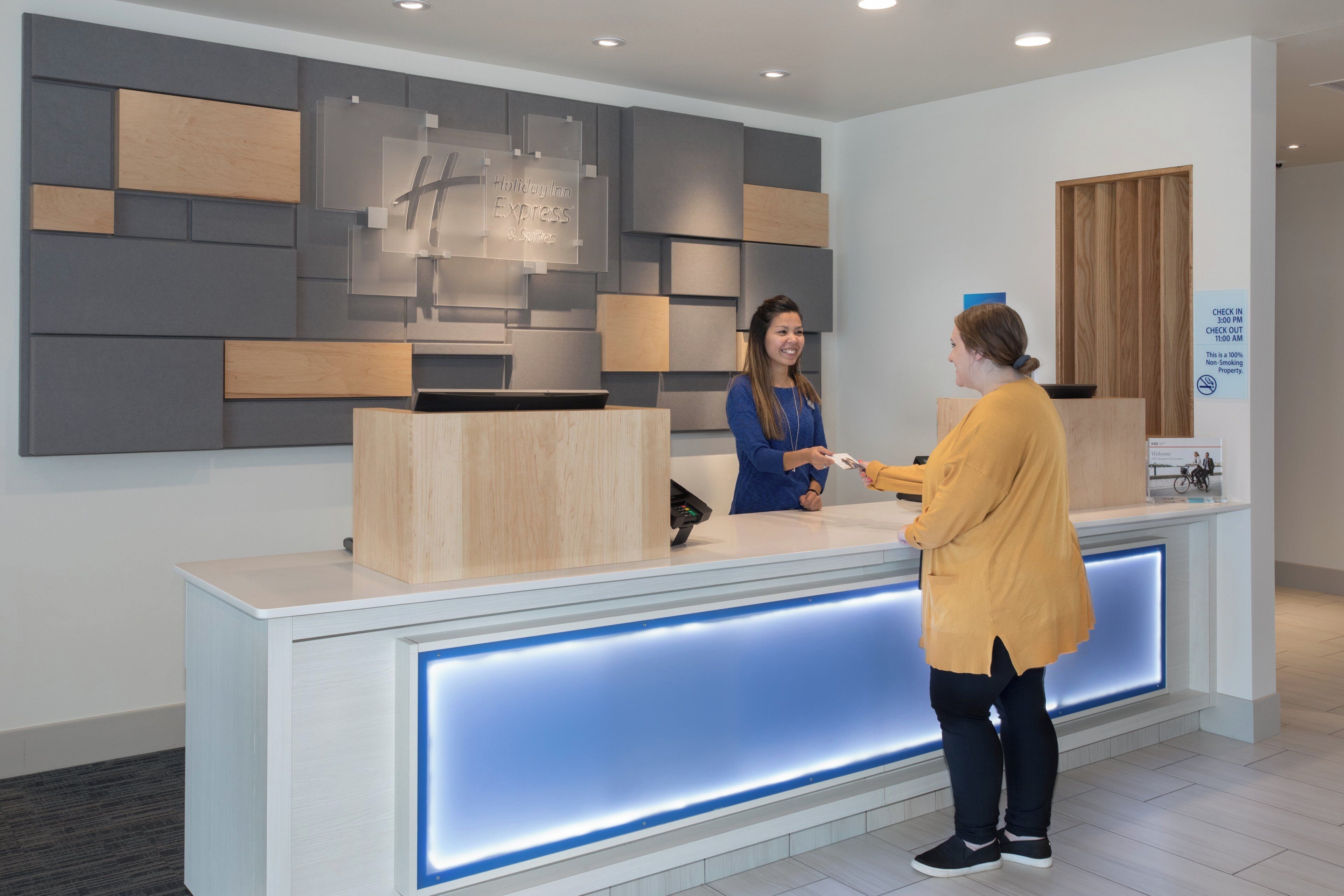 A reception desk with a modern design, a digital display, and a sign indicating check-in and check-out times.