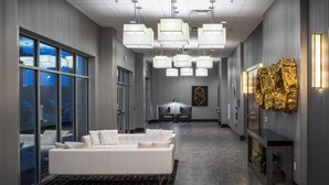 A modern lobby with a white sofa, pendant lighting, and a gold sculpture. - Holiday Inn Express & Suites Sioux City North-Event Center by IHG (North Sioux City)