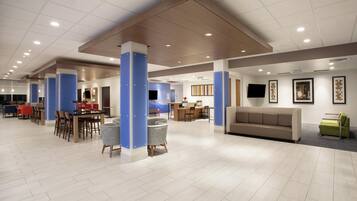 A spacious lobby with a reception desk, seating area, and a television mounted on the wall.