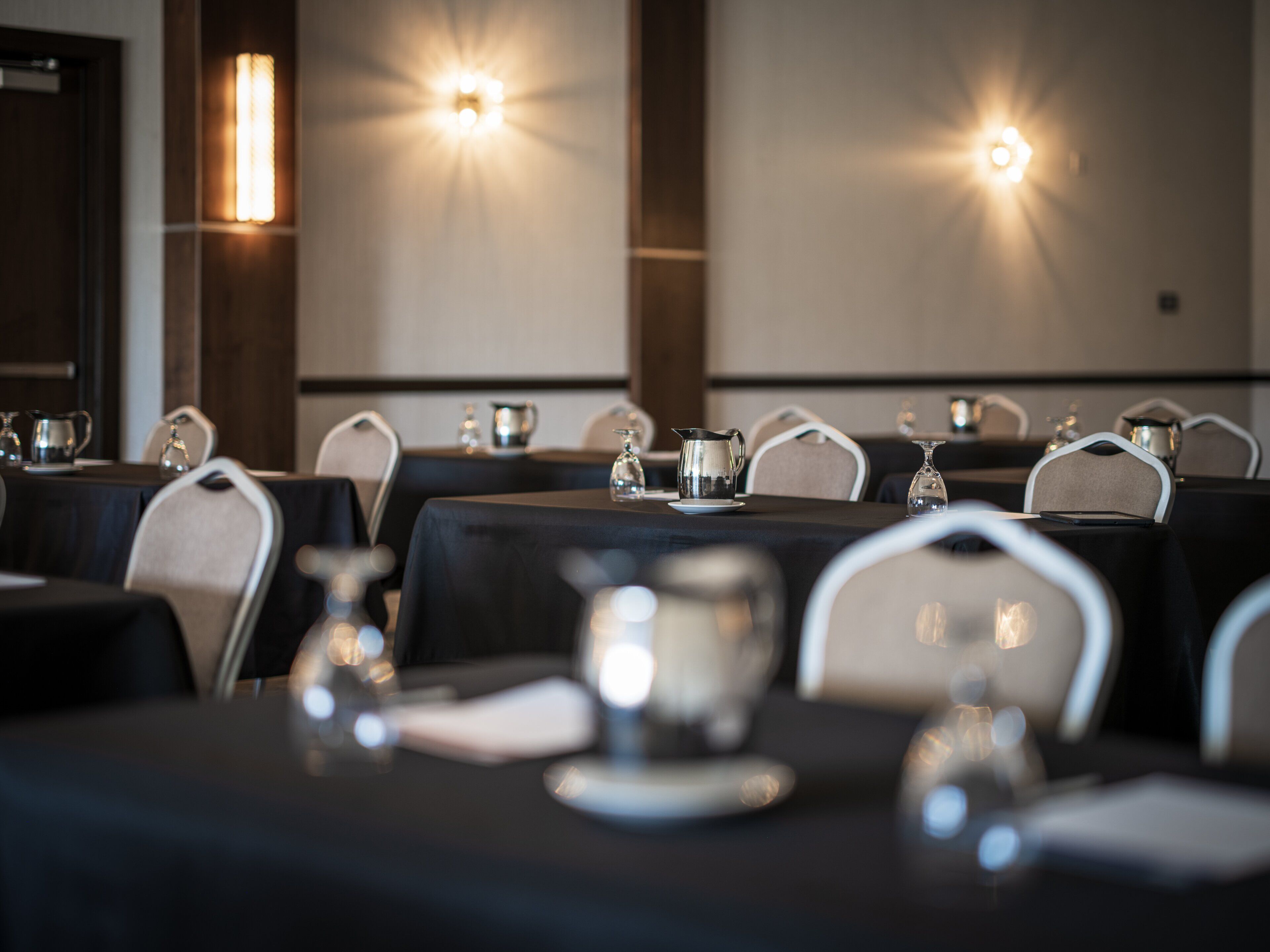 A conference room with tables set for a meeting, equipped with nameplates, water pitchers, and glasses.