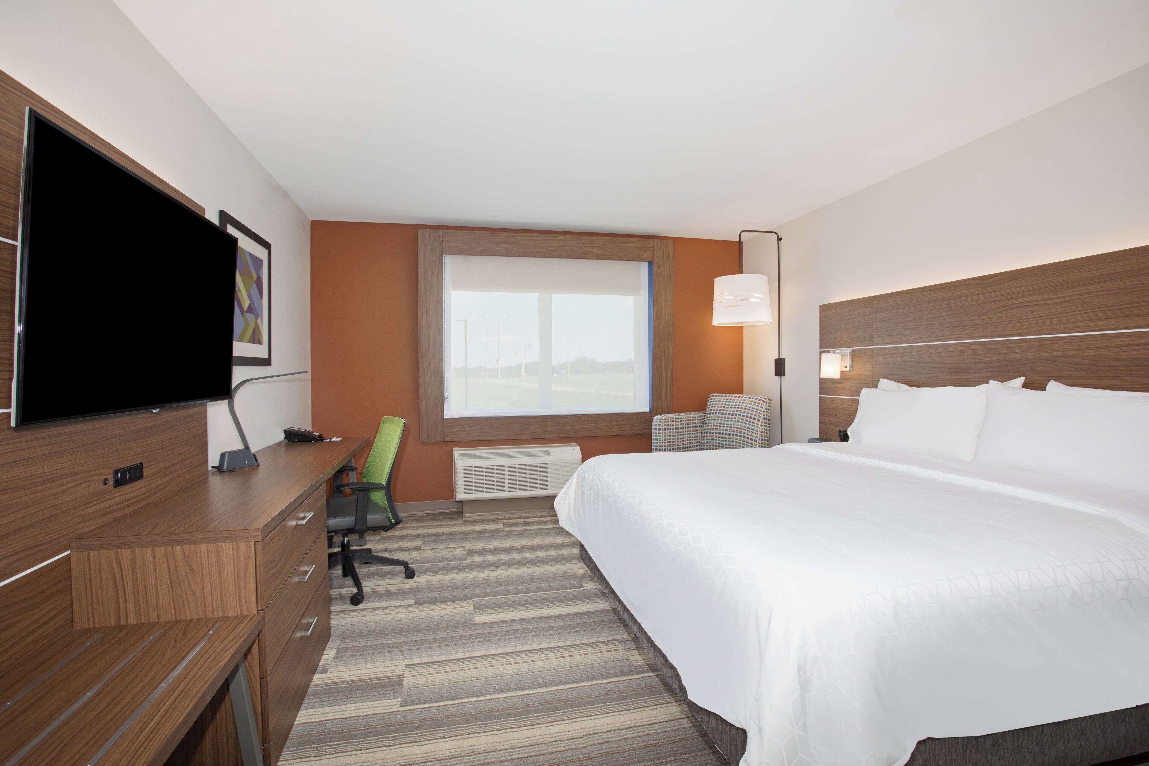 A hotel room with a bed, a desk, a chair, a television, and a window with a view.