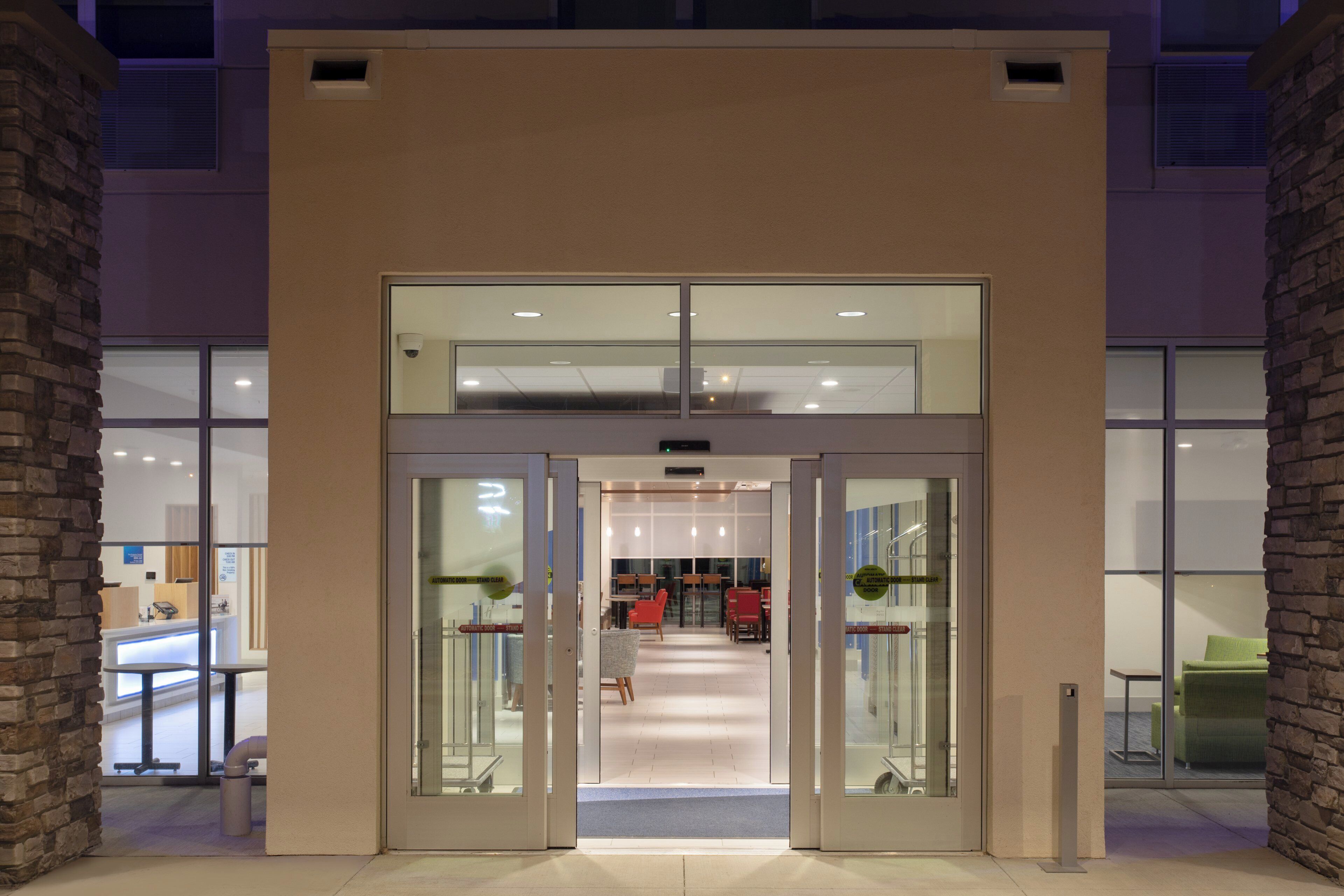 A hotel entrance with a double door, a reception desk, and a seating area visible through the glass doors.