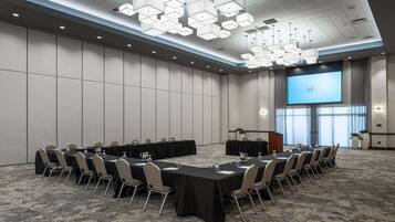 A conference room with a long table, chairs, a projector screen, and a podium.