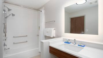 A modern bathroom with a bathtub, shower, and a vanity with a mirror.