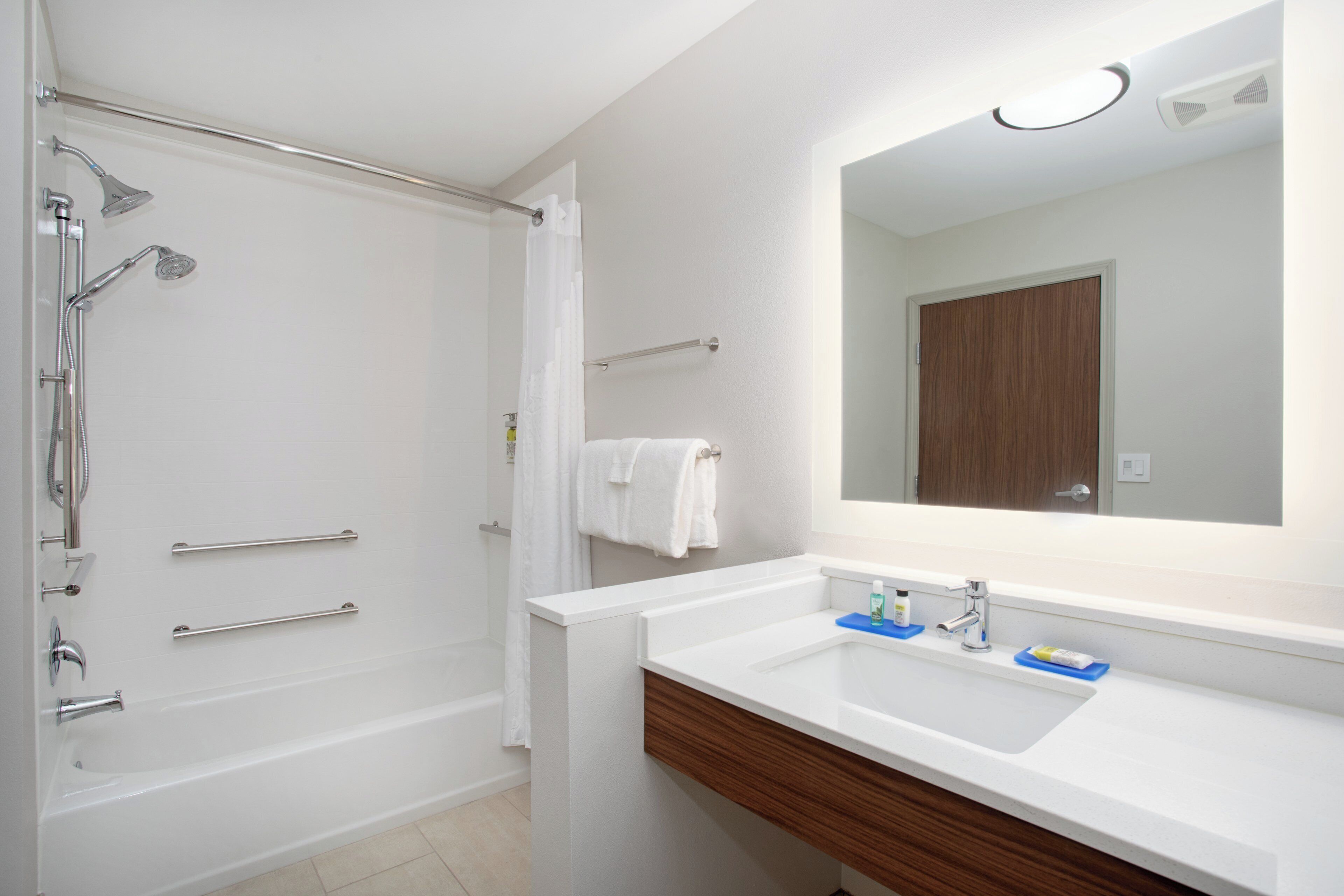A bathroom with a bathtub, shower, and a vanity with a mirror.