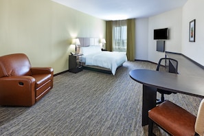 A hotel room with a bed, a desk, a chair, a TV, and a window with curtains.