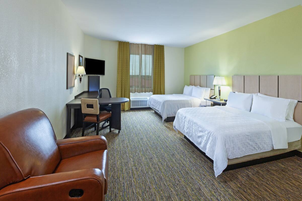 Een hotelkamer met twee bedden, een bureau, een stoel en een televisie.
