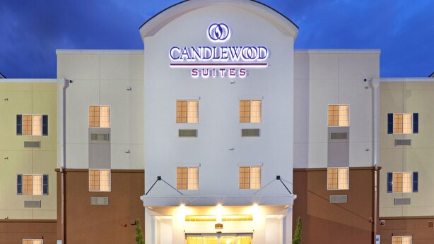 Un hôtel reconnaissable à son grand panneau « CANDLEWOOD SUITES », à ses nombreuses fenêtres et à sa façade plate.