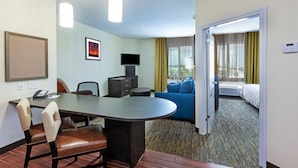 A hotel room with a dining area, a TV, a bed, and a view of the outdoors.