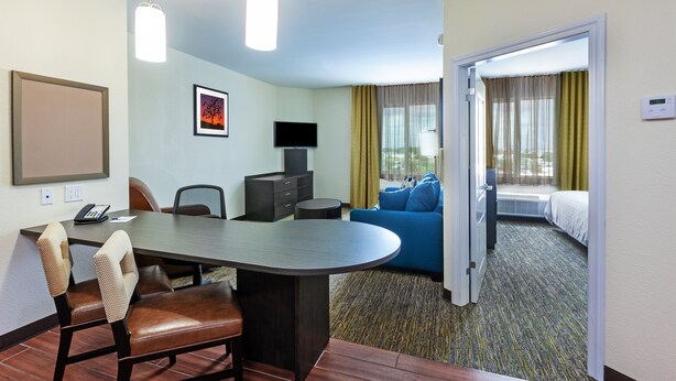 Habitación de hotel con comedor, televisión, cama y vistas al exterior.