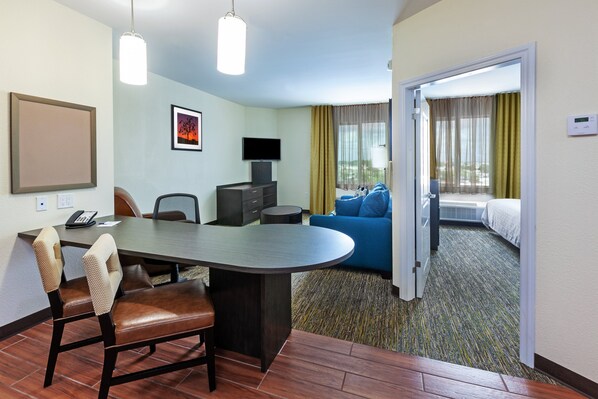 Habitación de hotel con comedor, televisión, cama y vistas al exterior.