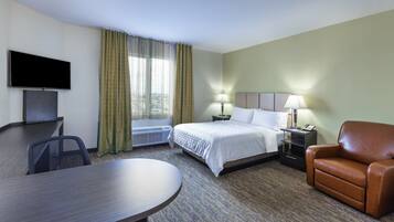A hotel room with a bed, a desk, a chair, a TV, and a window with curtains.