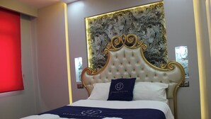 Una habitación de hotel con una cama grande, un cabecero decorativo y una obra de arte en la pared.