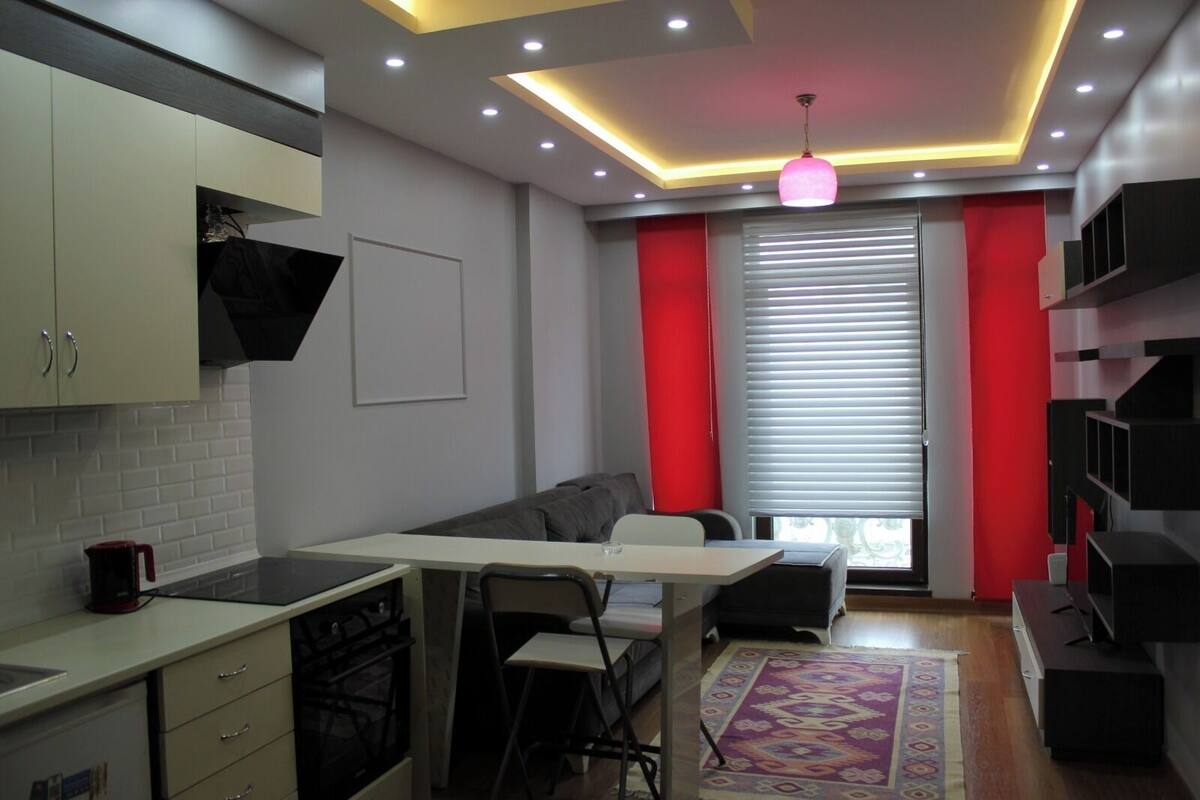 Una cocina compacta con comedor, un sofá y un ventanal con persianas.