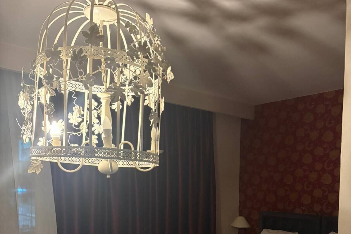 Una habitación de hotel con una cama grande, un sofá, una mesita pequeña y un candelabro decorativo.