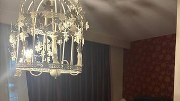 A hotel room with a large bed, a sofa, a small table, and a decorative chandelier.