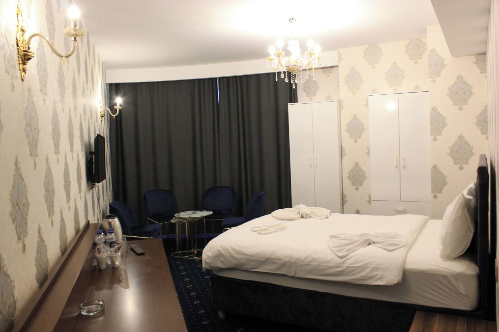 Et hotelværelse med en stor seng, et skrivebord med stol, et fjernsyn og et garderobeskab.