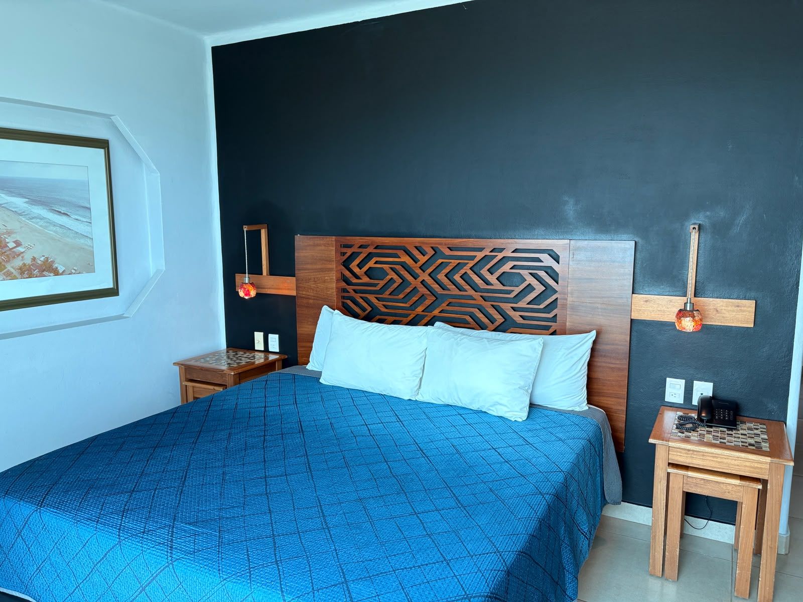 Een slaapkamer met een bed, een nachtkastje, een wandlamp en een ingelijste foto.