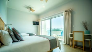 A hotel room with a bed, a desk, a chair, a TV, and a balcony with a view. - Hotel DC Boutique & SPA (Puerto Escondido)