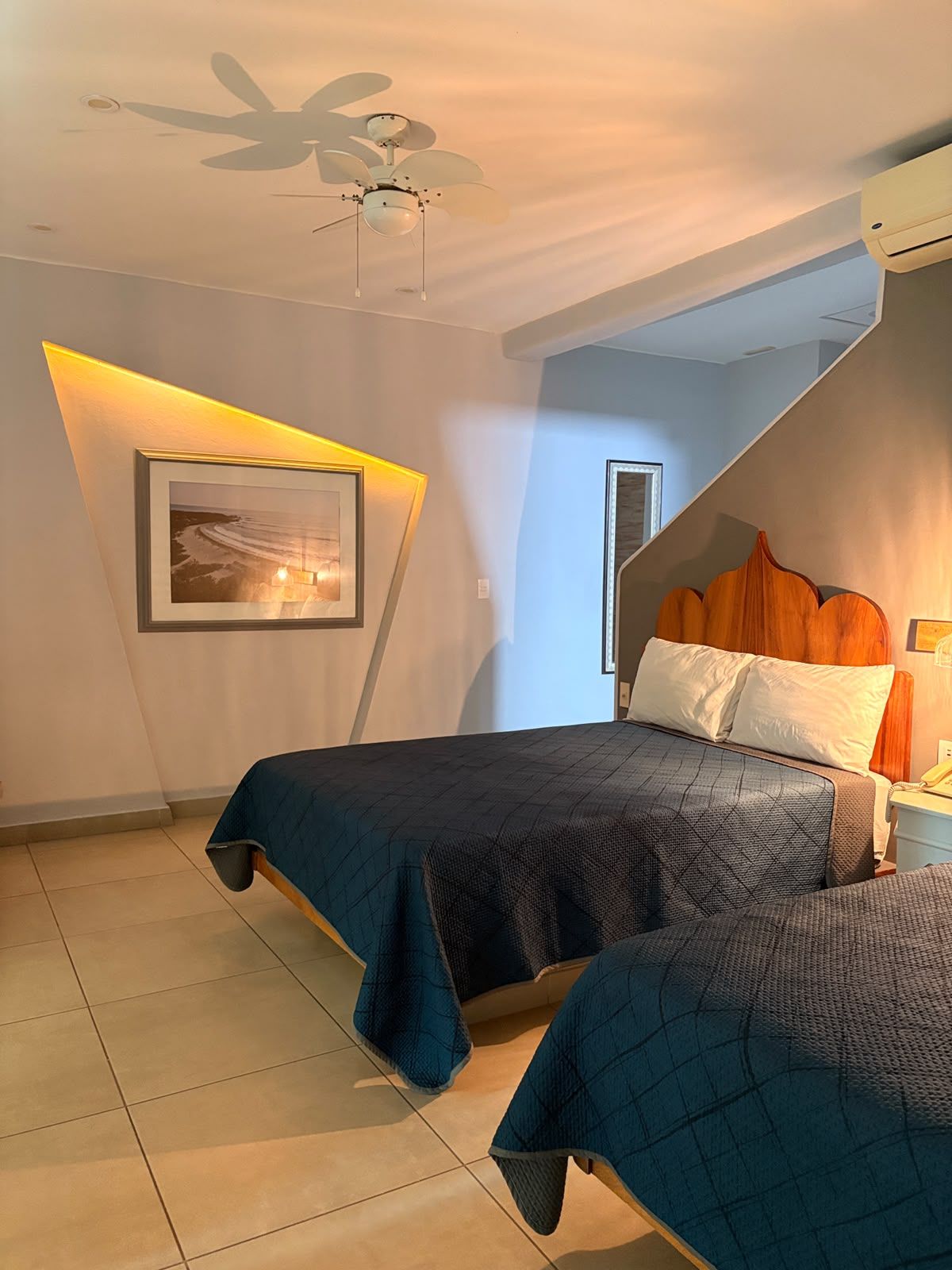 A bedroom with a bed, a bedside table, a framed picture, and a ceiling fan.