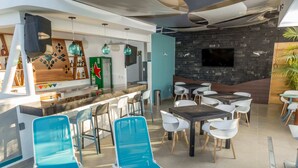 A modern bar area with a counter, seating, and a TV screen on the wall. - Hotel DC Boutique & SPA (Puerto Escondido)
