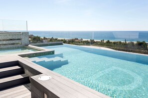 A clear view of a swimming pool with steps leading into it, surrounded by a wooden deck. - Hotel DC Boutique & SPA (Puerto Escondido)
