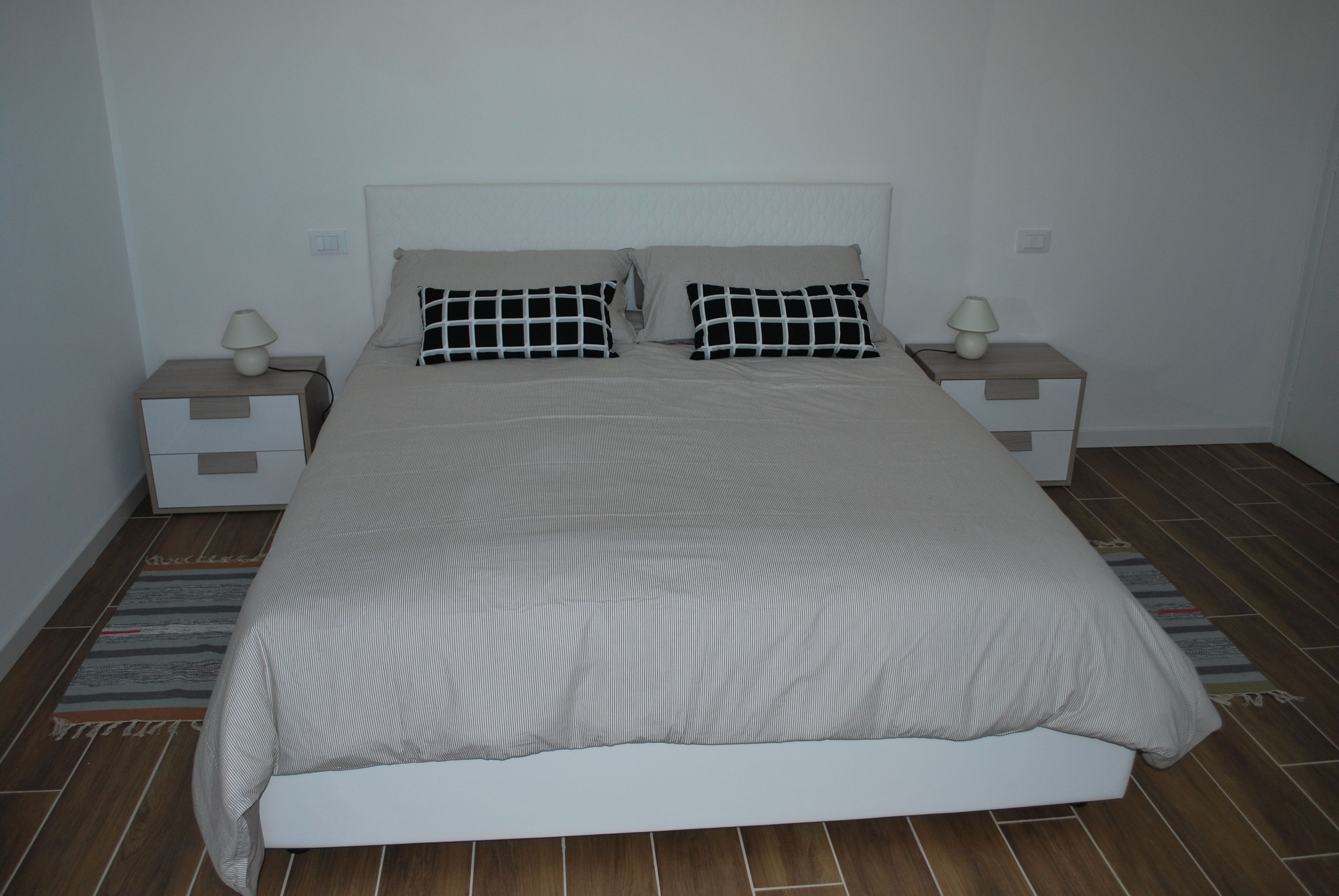 A bedroom with a bed, two nightstands, and a lamp on each side.