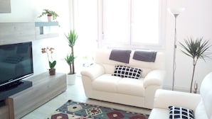 A living room with a white sofa, a flat-screen TV, and a large window. - Bed and Breakfast Bio Salix (Padova)