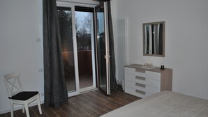 A bedroom with a bed, a chair, a dresser, a mirror, and a sliding glass door leading to a balcony. - Bed and Breakfast Bio Salix (Padova)
