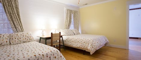 A bedroom with two beds, a ceiling fan, and a wooden floor.