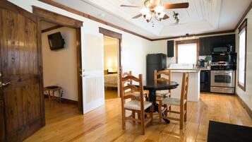 Une cuisine spacieuse avec un plancher en bois, un coin repas avec une table ronde et des chaises, et un ventilateur de plafond.