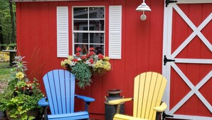 A red building with white shutters and a large white barn door. There are two Adirondack chairs, one blue and one yellow, in front of the building. -  Perfect getaway for couples ! close to Ludington!

 (Fountain)