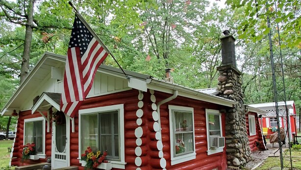A red log cabin with a chimney, a porch, and a flag. -  Perfect getaway for couples ! close to Ludington!

 (Fountain)