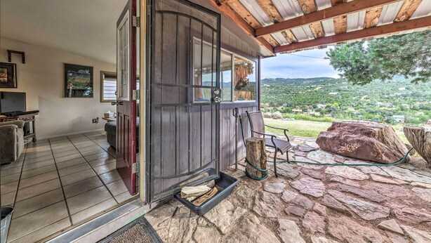 Un rincón acogedor con piso de piedra, una puerta de madera que da al exterior y vista a un paisaje exuberante.