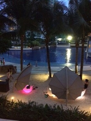 A poolside area with umbrellas and lounge chairs, surrounded by palm trees. - (Parañaque)