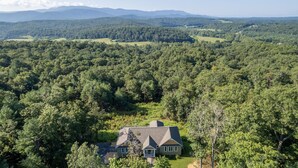 A house surrounded by dense forest with a clear view of distant mountains. - Shenandoah mountain view home King bed StarLink EV port river access 90 min DC  (Bentonville)