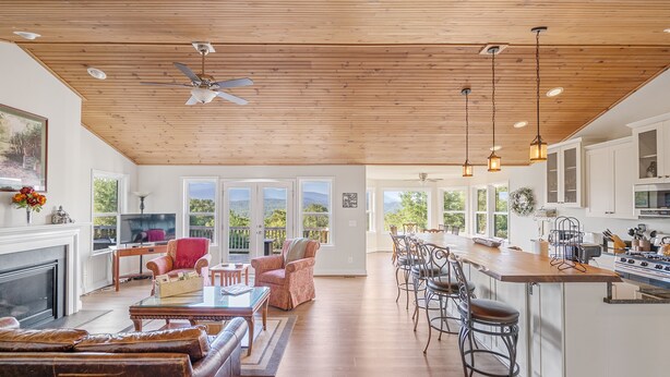 A spacious living area with a fireplace, a dining table, and a kitchen with a large island. - Shenandoah mountain view home King bed StarLink EV port river access 90 min DC  (Bentonville)