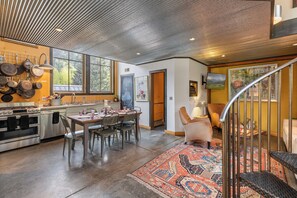 A modern kitchen with stainless steel appliances, a dining area with a patterned rug, and a staircase leading to a living area. - Galena Chalet – 1BR Sleeps 4 - Rare Find Retreat (Telluride)