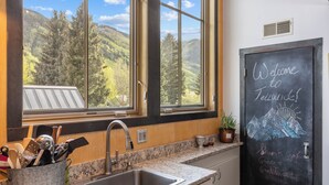 Et køkken med et stort vindue, en vask og en tavle med teksten 'Welcome to Telluride!'.