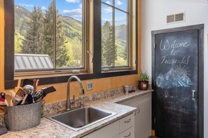 A kitchen with a large window, a sink, and a chalkboard with 'Welcome to Telluride!' written on it. - Galena Chalet – 1BR Sleeps 4 - Rare Find Retreat (Telluride)