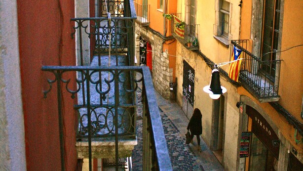 A narrow street with buildings on either side, balconies with metal railings, and a cobblestone pavement. - Charming flat next to the Cathedral (Girona)