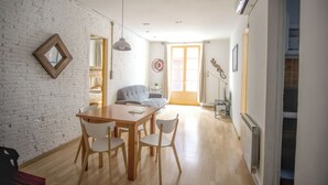 A dining area with a wooden table and chairs, a sofa, and a brick wall. - Charming flat next to the Cathedral (Girona)